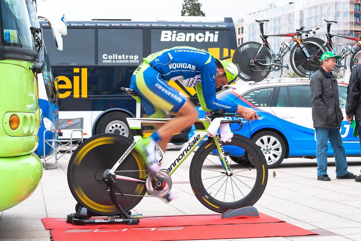 Cyklista se rozjíždí na časovkářském kole upnutém do trenažéru před startem časovky