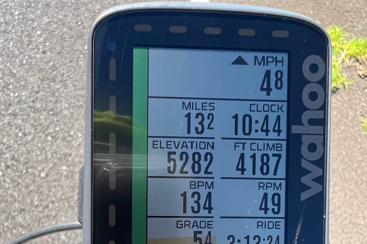 GPS cyklopočítač uchycený na představci silničního kola zobrazuje rychlost, ujeté kilometry, převýšení, tepovou frekvenci a kadenci